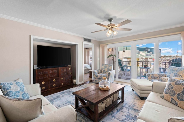 living room with crown molding, a textured ceiling, ceiling fan, and light wood-type flooring