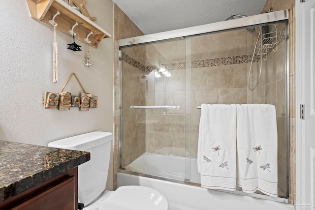 full bathroom featuring vanity, toilet, combined bath / shower with glass door, and a textured ceiling