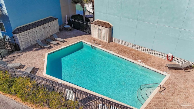 view of pool featuring a storage shed and a patio area