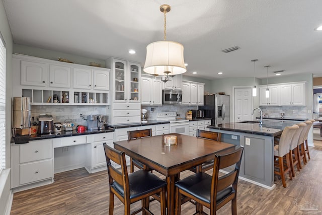 2215 Seascale Ct, Navarre, FL 32566 - kitchen with appliances with stainless steel finishes, dark countertops, a sink, decorative backsplash, and dark wood-style flooring