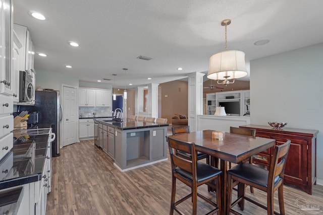 2215 Seascale Ct, Navarre, FL 32566 - kitchen featuring decorative columns, stainless steel appliances, a sink, dark countertops, and dark wood-type flooring