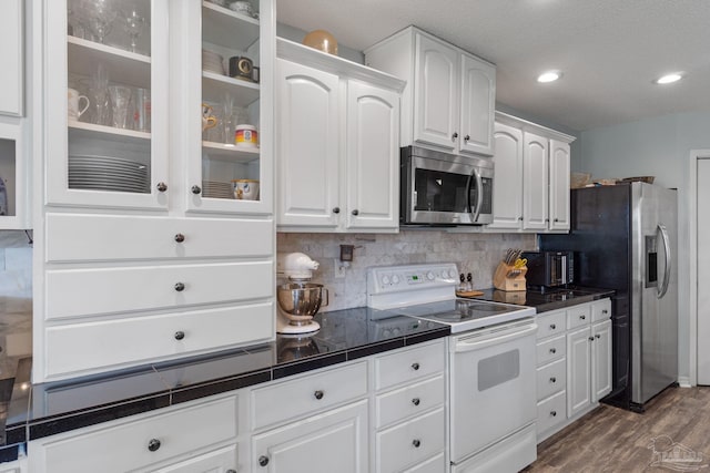 2215 Seascale Ct, Navarre, FL 32566 - kitchen with appliances with stainless steel finishes, white cabinetry, tasteful backsplash, glass insert cabinets, and dark wood-type flooring