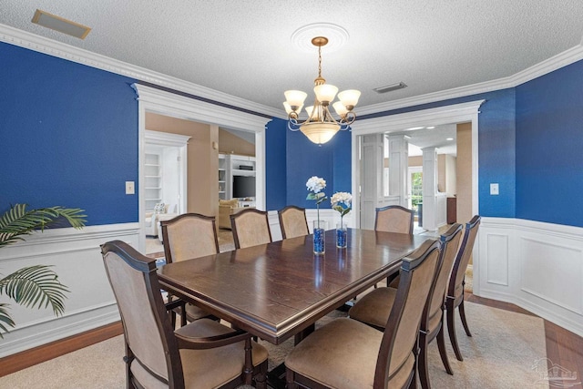 2215 Seascale Ct, Navarre, FL 32566 - dining room with a chandelier, a textured ceiling, ornamental molding, wainscoting, and ornate columns