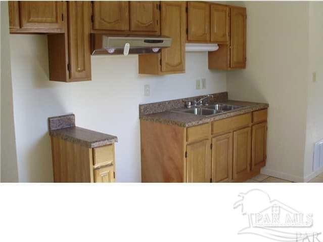 kitchen with range hood, light tile patterned floors, and sink