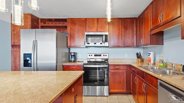 kitchen with pendant lighting, light stone counters, light tile patterned flooring, sink, and stainless steel appliances