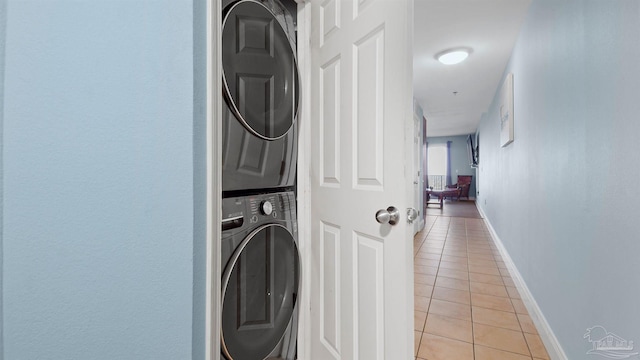 laundry room with light tile patterned floors and stacked washer / drying machine