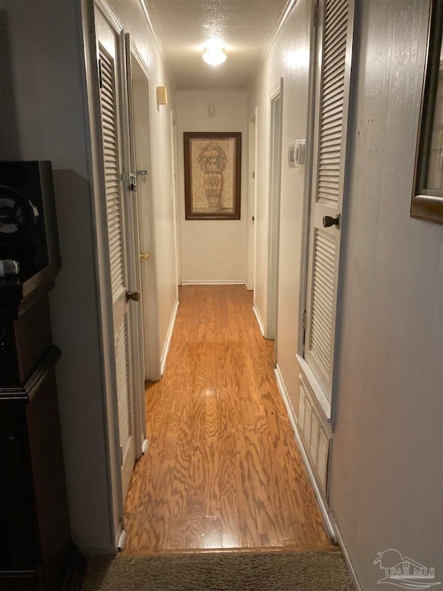 corridor featuring light hardwood / wood-style flooring and a textured ceiling