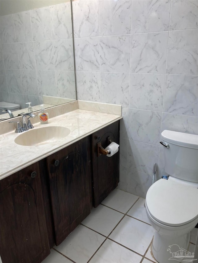 bathroom featuring vanity, tile walls, toilet, and tile patterned floors