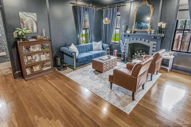 living room featuring a wealth of natural light, hardwood / wood-style floors, and a brick fireplace