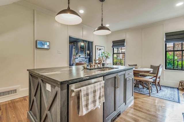 kitchen featuring sink, wine cooler, decorative light fixtures, a center island with sink, and light wood-type flooring