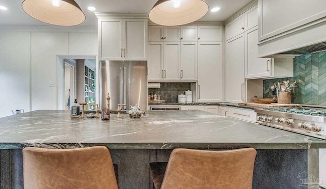 kitchen featuring a kitchen bar, tasteful backsplash, a spacious island, high quality appliances, and dark stone countertops