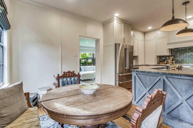 kitchen with pendant lighting, backsplash, dark stone counters, high end refrigerator, and light wood-type flooring