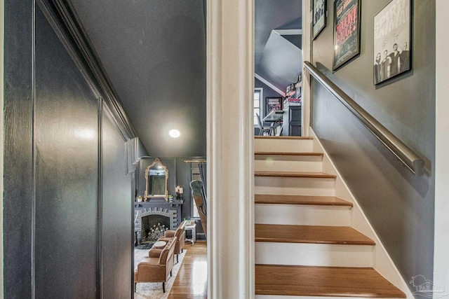 stairs with hardwood / wood-style flooring and a brick fireplace