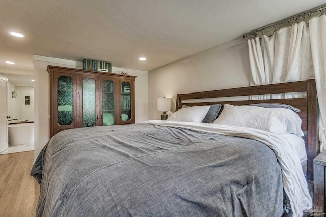 bedroom with light hardwood / wood-style floors and ensuite bath