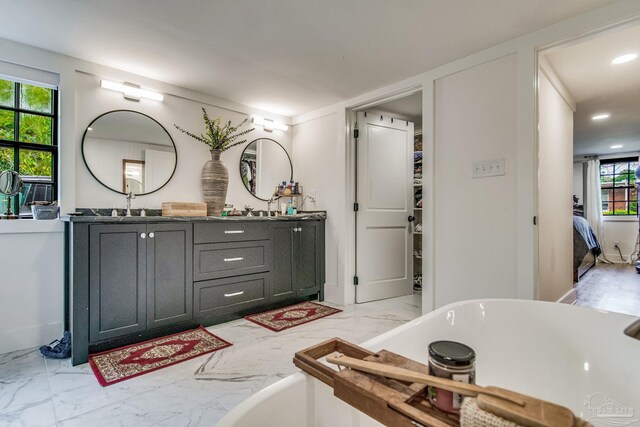 bathroom with plenty of natural light, a bath, and vanity