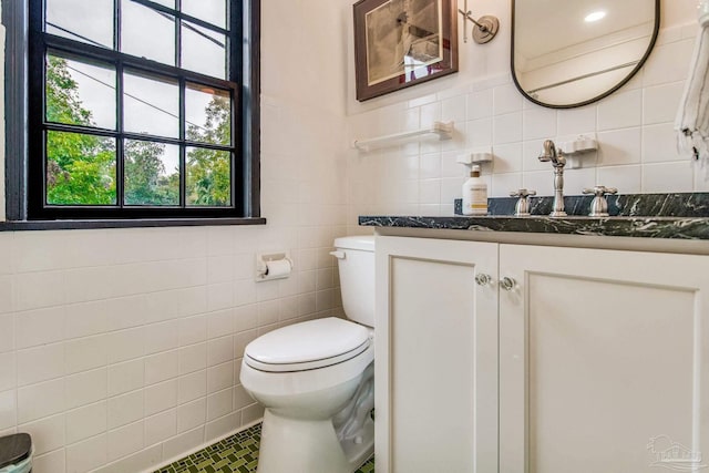 bathroom featuring vanity, toilet, and tile walls