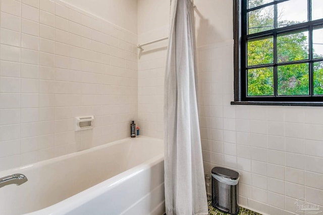 bathroom with a healthy amount of sunlight and shower / bathtub combination with curtain