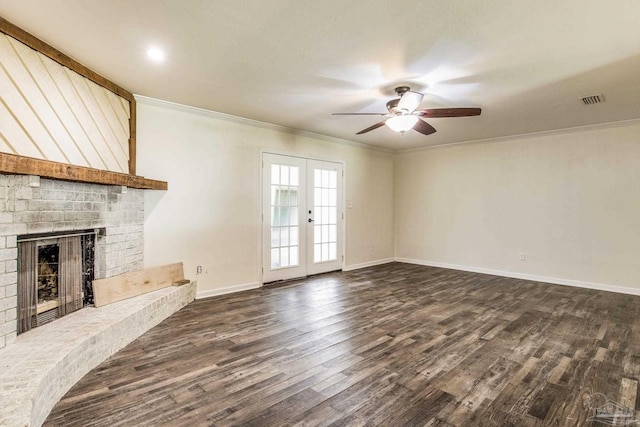 unfurnished living room with crown molding, a brick fireplace, dark hardwood / wood-style floors, and french doors