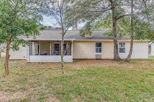 rear view of house featuring a sunroom and a yard