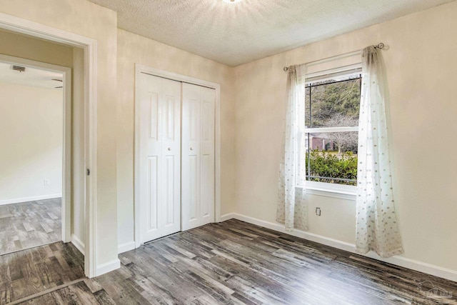 unfurnished bedroom featuring dark hardwood / wood-style flooring, a closet, and a textured ceiling