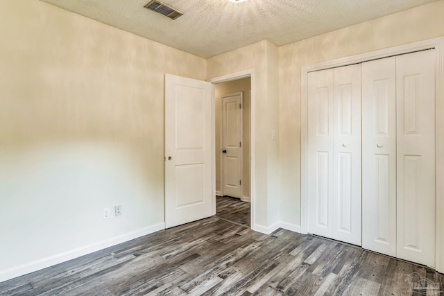 unfurnished bedroom featuring dark wood-type flooring, a closet, and a textured ceiling