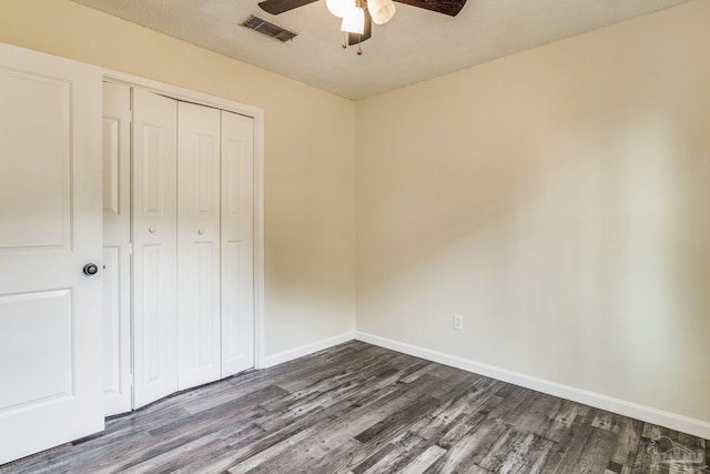 unfurnished bedroom featuring ceiling fan, dark hardwood / wood-style flooring, and a closet