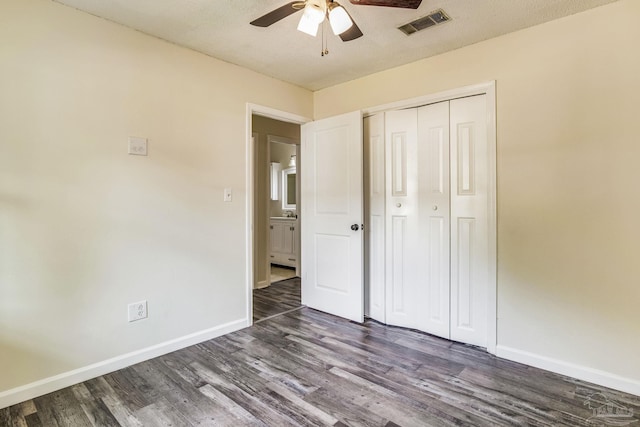 unfurnished bedroom featuring a closet, a textured ceiling, dark hardwood / wood-style floors, and ceiling fan