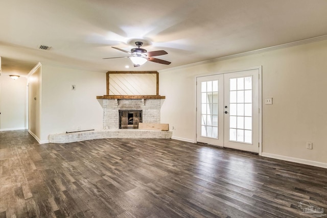 unfurnished living room featuring dark hardwood / wood-style flooring, crown molding, a fireplace, and french doors