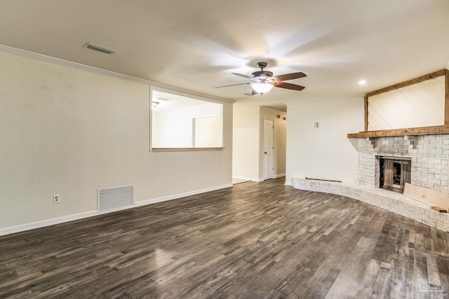 unfurnished living room with a brick fireplace, crown molding, dark hardwood / wood-style floors, and ceiling fan