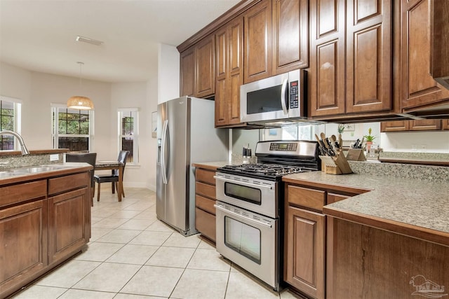 kitchen featuring hanging light fixtures, appliances with stainless steel finishes, sink, and light tile patterned floors