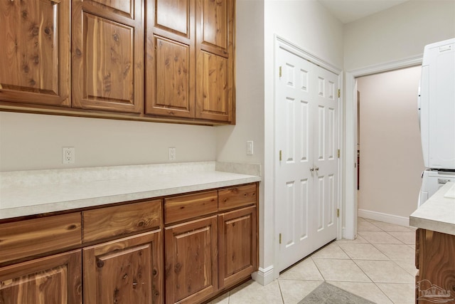 kitchen with light tile patterned floors and stacked washer / dryer