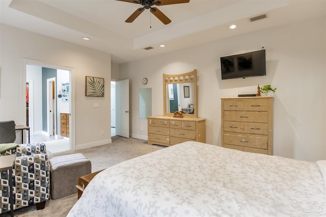 carpeted bedroom featuring ceiling fan and a tray ceiling