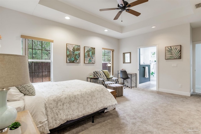 carpeted bedroom with a raised ceiling and ceiling fan