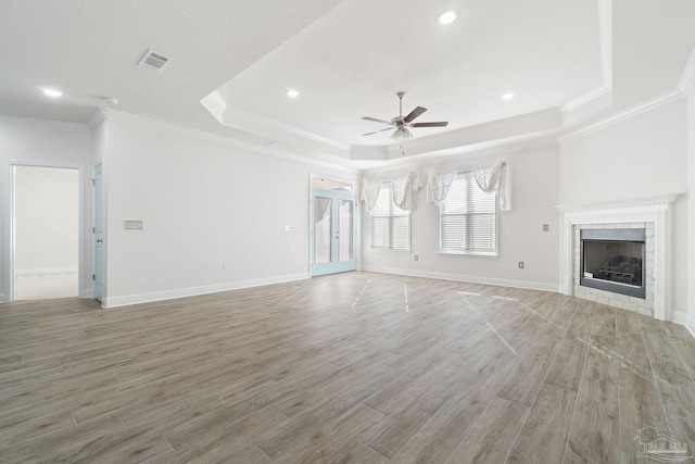 2339 Habersham Ln, Cantonment, FL 32533 - unfurnished living room with baseboards, a tiled fireplace, a ceiling fan, wood finished floors, and a tray ceiling