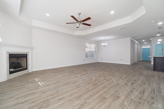 2339 Habersham Ln, Cantonment, FL 32533 - unfurnished living room with light wood finished floors, baseboards, a raised ceiling, a tile fireplace, and ceiling fan with notable chandelier