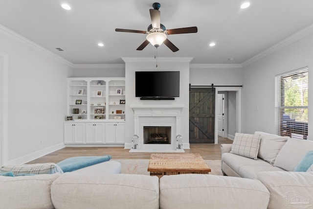 living room featuring crown molding, a barn door, light wood-type flooring, and ceiling fan