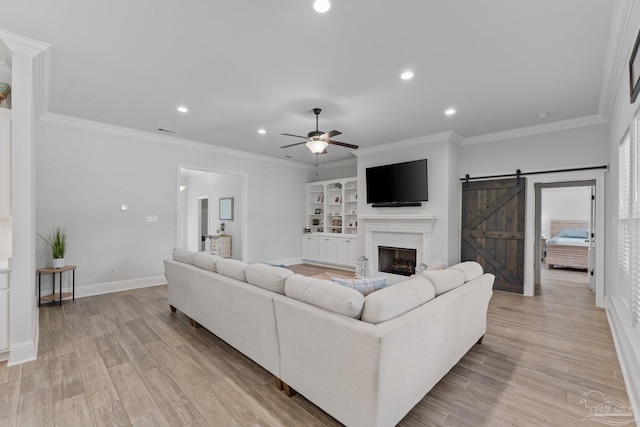 living room featuring crown molding, a barn door, light wood-type flooring, and ceiling fan