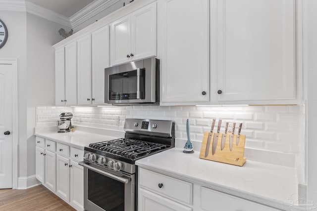 kitchen featuring stainless steel appliances, crown molding, white cabinets, light hardwood / wood-style floors, and tasteful backsplash