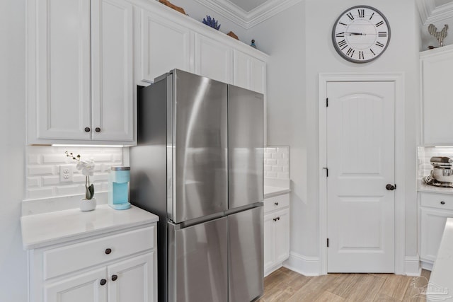 kitchen featuring light hardwood / wood-style flooring, backsplash, stainless steel fridge, crown molding, and white cabinets