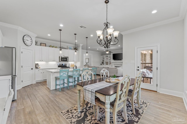 dining space featuring an inviting chandelier, ornamental molding, and light wood-type flooring