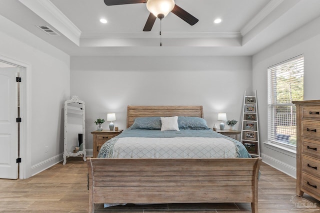 bedroom with ceiling fan, a raised ceiling, ornamental molding, and light hardwood / wood-style flooring