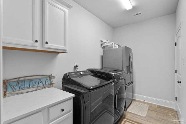 laundry room featuring cabinets, light hardwood / wood-style flooring, and independent washer and dryer