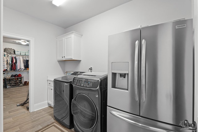 clothes washing area with light hardwood / wood-style floors, cabinets, and washing machine and dryer