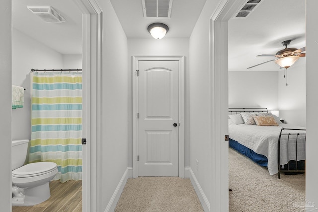 interior space with toilet, walk in shower, wood-type flooring, and ceiling fan