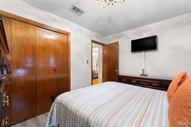 bedroom featuring a textured ceiling, light wood-type flooring, and a closet