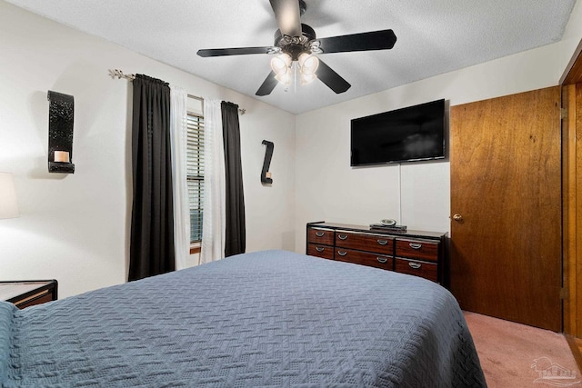 carpeted bedroom featuring ceiling fan and a textured ceiling