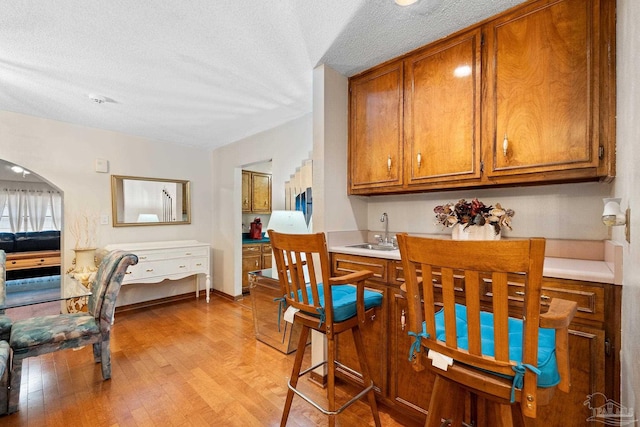 dining room with sink, light hardwood / wood-style floors, and a textured ceiling