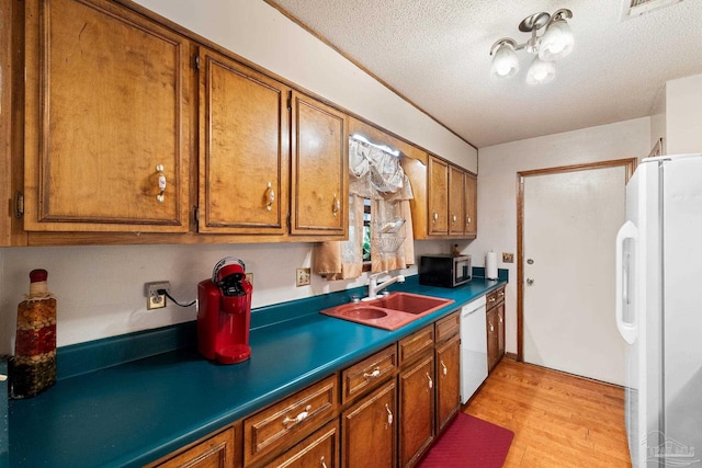 kitchen featuring a textured ceiling, sink, white appliances, and light wood-type flooring