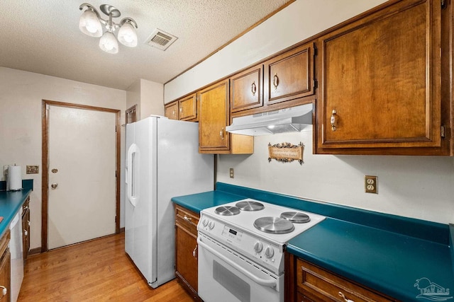 kitchen with a textured ceiling, white appliances, and light hardwood / wood-style floors