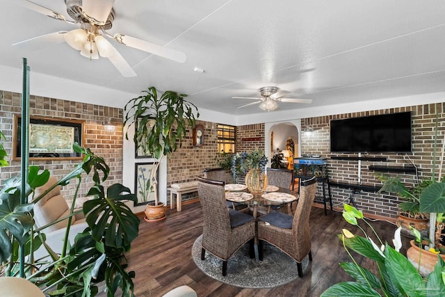 dining space featuring dark hardwood / wood-style floors and brick wall